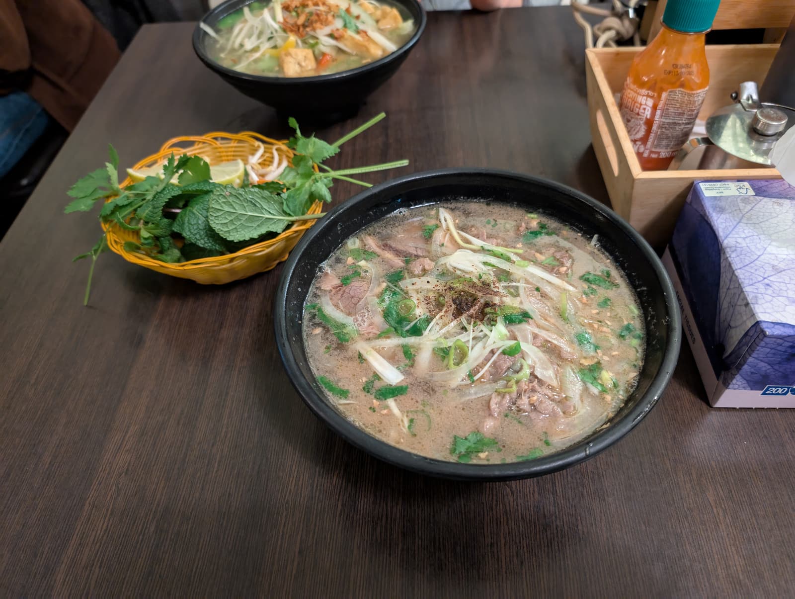A bowl of beef pho with herbs